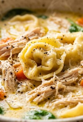 Ultra close-up macro of creamy chicken tortellini soup with spinach and cheese